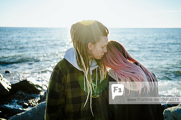 Affectionate lesbian couple standing near sea