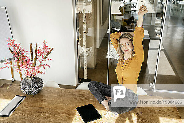 Businesswoman stretching arm sitting on desk
