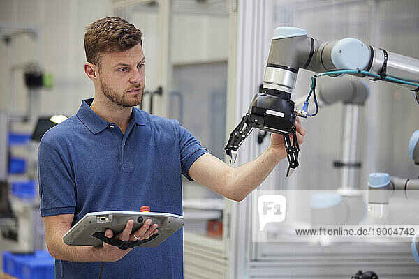 Engineer testing modern robotic arm in factory
