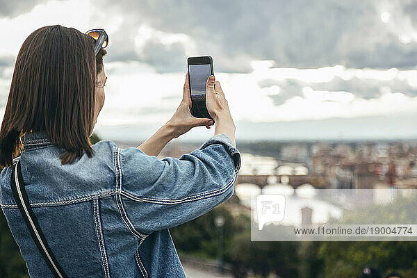 Woman photographing city through smart phone