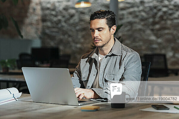 Architect using laptop sitting on table in office