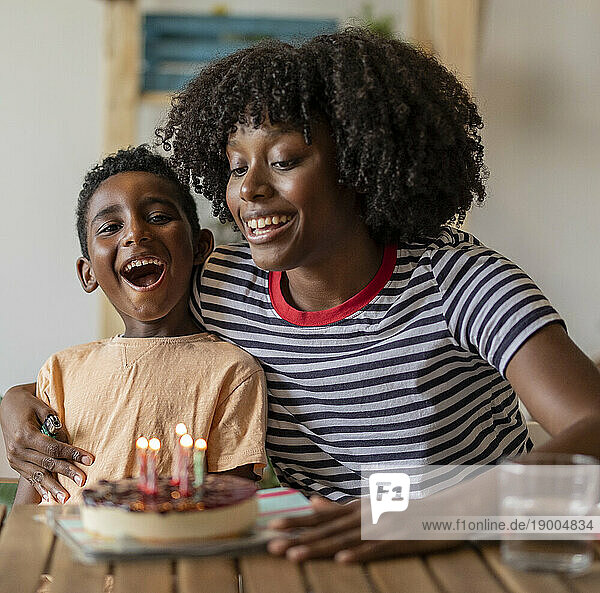 Happy mother celebrating birthday of son with cake