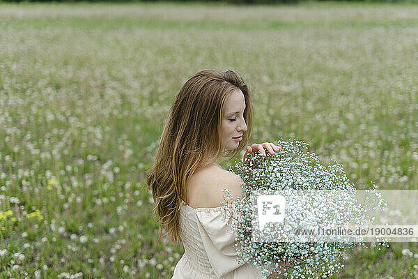 Young woman holding wildflower bouquet on field