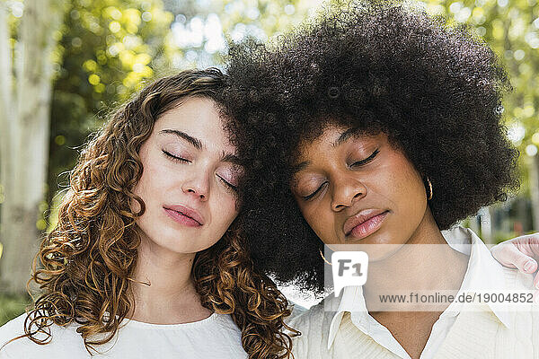 Multiracial friends with eyes closed in park