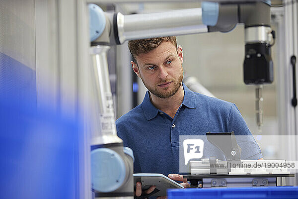 Focused engineer examining robotic machine in industry