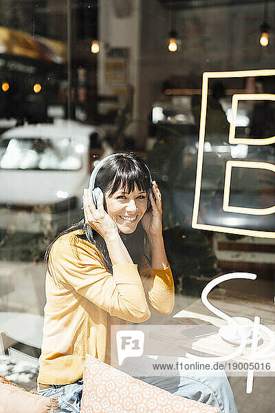Smiling woman wearing wireless headphones listening to music