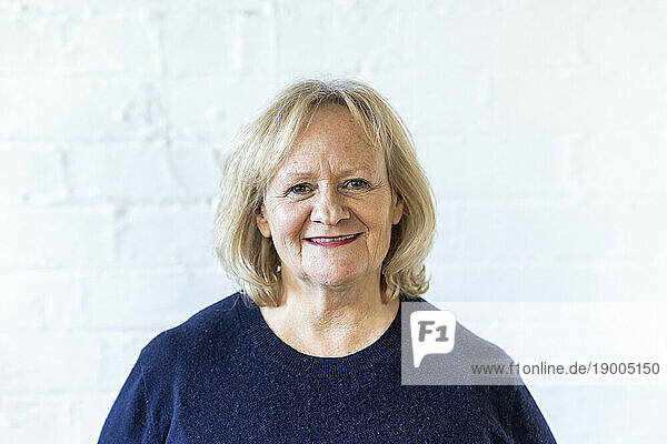 Happy senior businesswoman in front of white wall