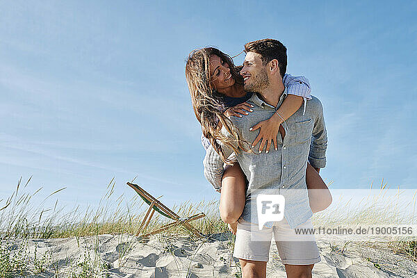 Romantic man piggybacking girlfriend at beach