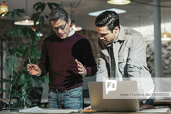 Architect father and son discussing in office