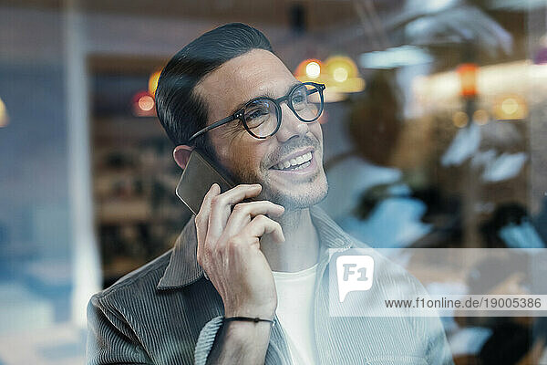 Smiling architect talking on smart phone in office