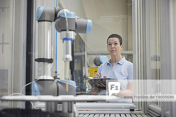 Concentrated engineer examining robotic machine in industry
