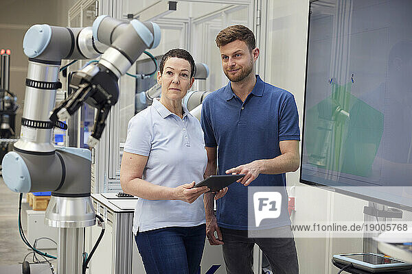 Technicians examining modern machine part standing in industry