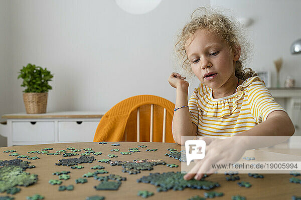 Girl solving jigsaw puzzle at home