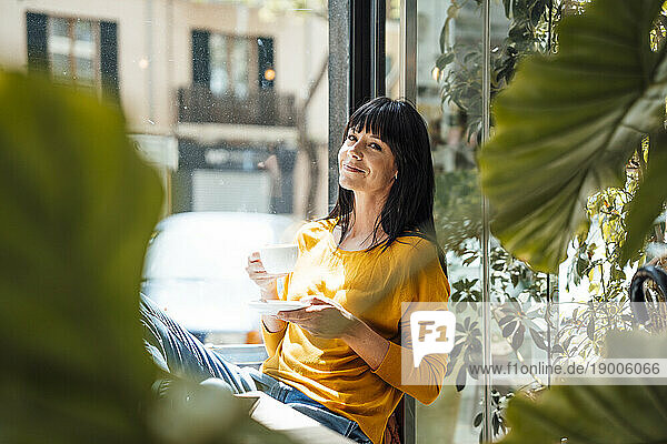 Smiling woman sitting with coffee cup in cafe