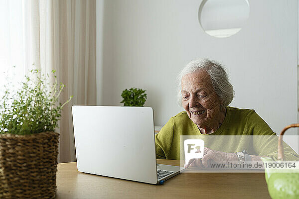 Senior woman using laptop on table at home