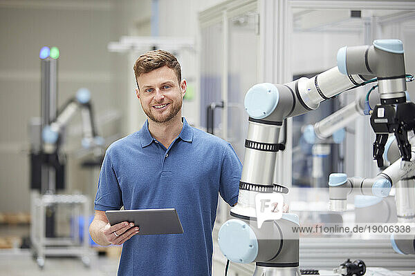 Smiling technician standing next to modern machine in industry