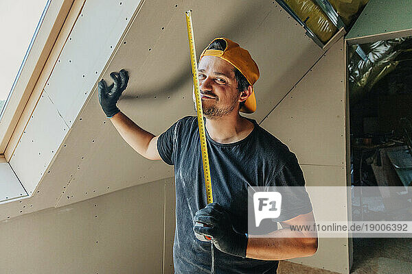 Man standing with measuring tape in attic