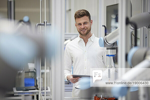 Smiling technician holding tablet PC in industry