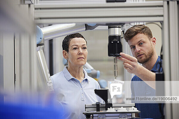 Technician explaining machine part to colleague in industry