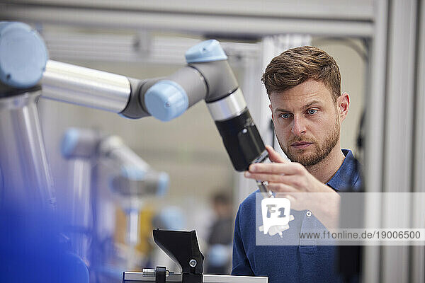 Focused engineer holding robotic arm in modern factory