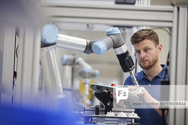 Engineer testing robotic arm using equipment in industry