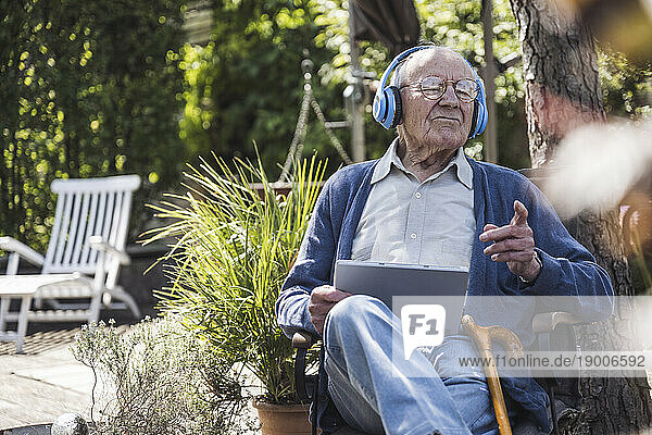 Senior man wearing wireless headphones listening to music