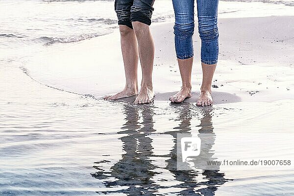 Die Beine von zwei Menschen  die sich im Meer spiegeln