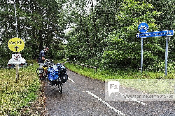 Blaue Verkehrsschilder  Radfahrer  Radwanderer auf Radweg im Regen  origineller Wegweiser mit Aufschrift  Tor zum Paradies  Eden Project  Cornwall  Großbritannien  Europa