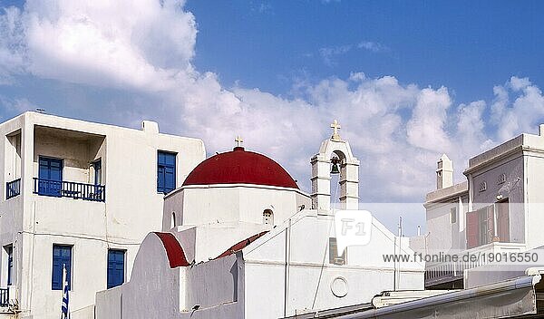 Schöne Nahaufnahme einer traditionellen griechisch orthodoxen Kirche in einer typischen griechischen Inselstadt. Rote Kuppel  weiß getünchte Wände und Glockenturm. Sommertag Sonnenschein  blauer Himmel und leichte Wolken. Mykonos  Kykladen  Griechenland  Europa
