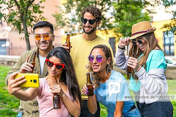 Multiethnische Gruppe von Freunden  die im Stadtpark feiern und ein Selfie machen  Freundschaft und Spaßkonzept mit Sonnenbrille und Bier trinken
