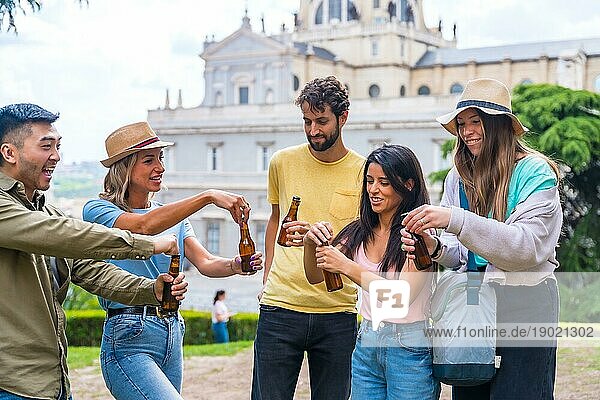 Eine multiethnische Gruppe von Freunden feiert in einem Stadtpark mit Bier