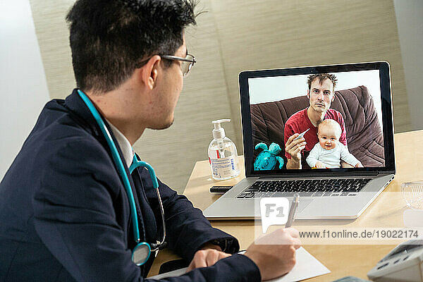 Pediatrician in remote consultation with a father and his infant with temperature