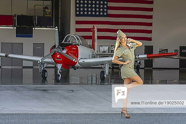 Ein schönes blondes Model posiert mit einem alten WWII Flugzeug