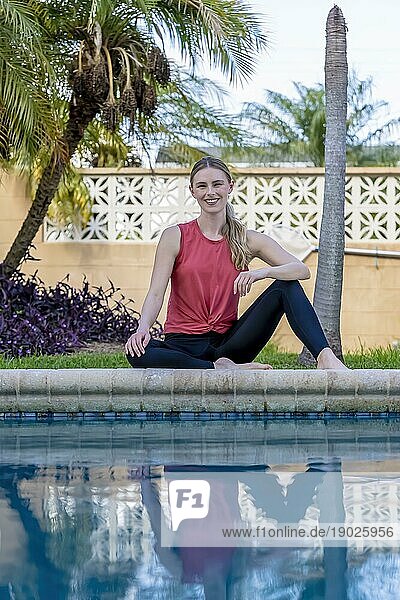Ein wunderschönes blondes Model macht Yoga  während sie an einem Sommertag einen Tag am Pool genießt