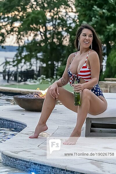 Porträt einer Frau  die einen patriotischen amerikanischen Bikini trägt  während sie einen Sonnenuntergang in einer Sommernacht genießt