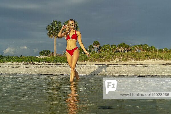 Ein schönes blondes Bikinimodell genießt das Wetter draußen am Strand