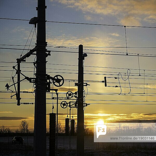 Eisenbahnmast und Kabel bei Sonnenaufgang