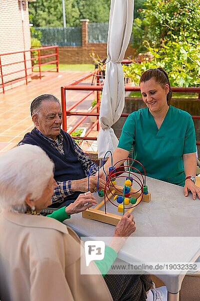 Zwei ältere Menschen im Garten eines Pflegeheims oder Seniorenheims  die mit Spielen die Beweglichkeit der Hände verbessern