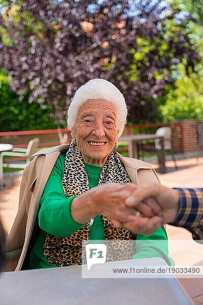 Hände zweier älterer Menschen im Garten eines Pflegeheims oder einer Pension  die sich in einem Moment der Zuneigung an den Händen halten