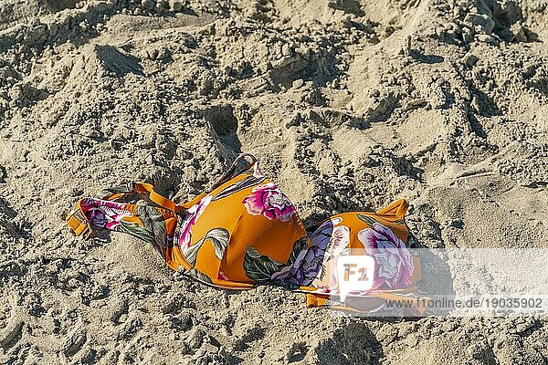 Ein Bikinioberteil liegt im Sand an einem örtlichen Strand