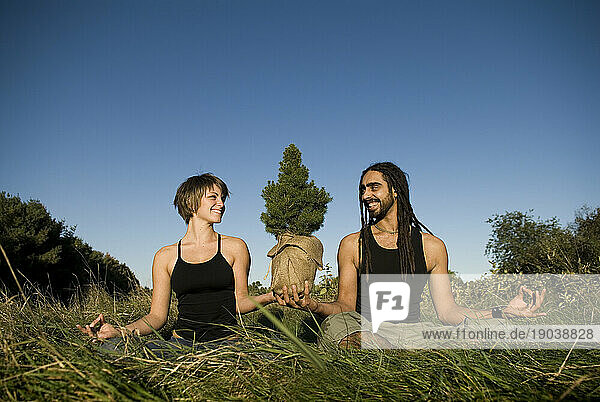 A man and woman doing yoga while together holding a tree  Maine.