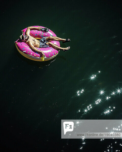 Looking down on a man floating on a inflatable inner tube.