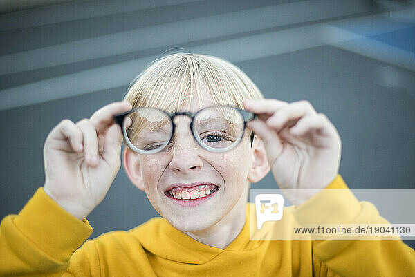 Kid holding out eyeglasses and looking through them