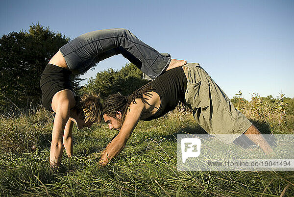 Man and woman practicing yoga in a field  Maine.