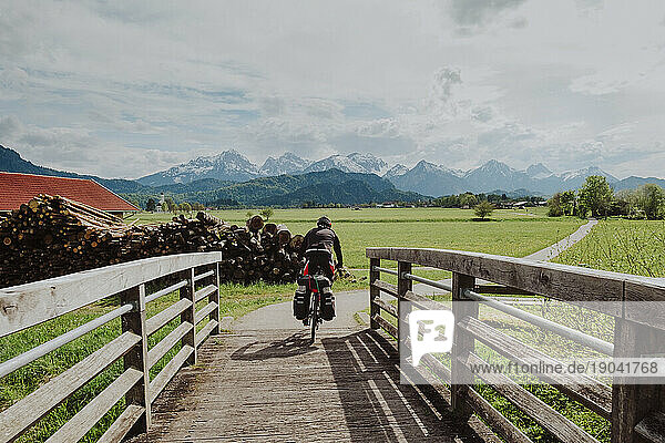 A biker cross the bridge with big mountains of The Alps in the front