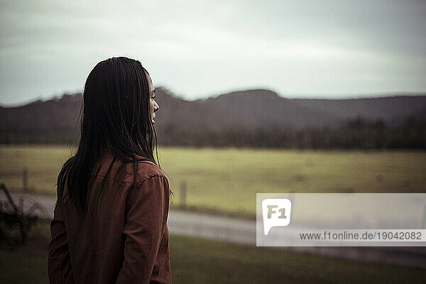 Asian girl looks out at country at dusk