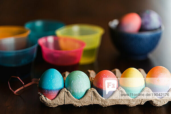 Colorful Easter eggs and dye containers on a wooden table.