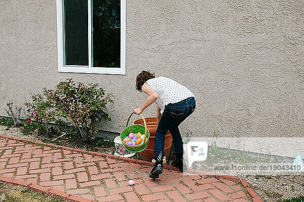 Back of a girl reaching into a pot searching for Easter eggs