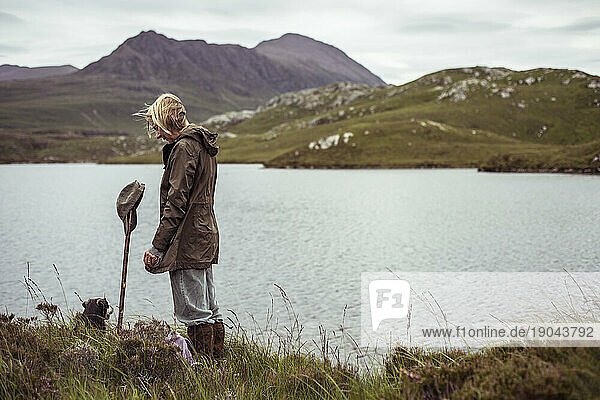 retire woman stands alone by loch in scottish highlands