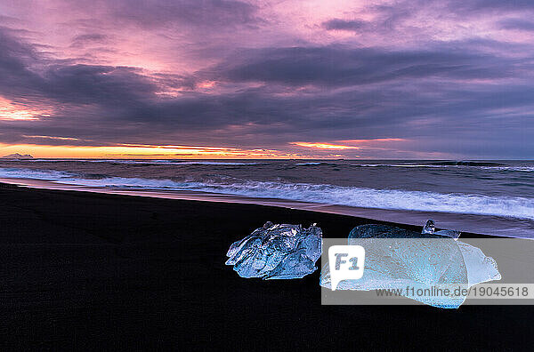 Sunset with blocks of ice in black sand beach  Iceland